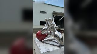 Het gespiegelde roestvrijstalen bowlingsculptuur legt het dynamische moment levendig vast